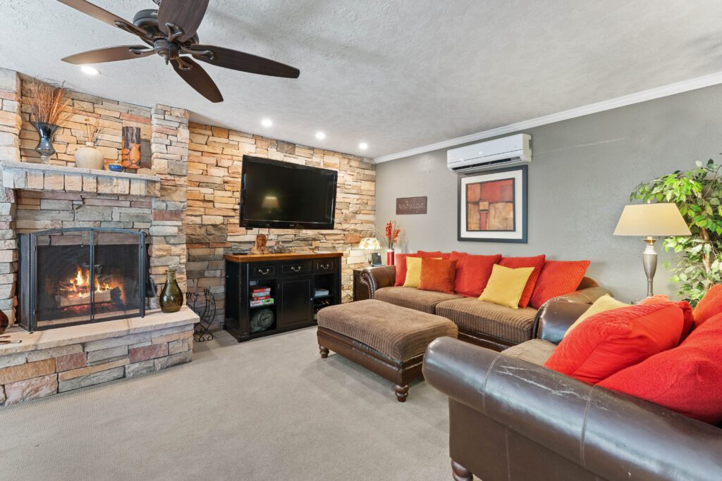 A living room with couches, a fireplace and a flat screen tv.