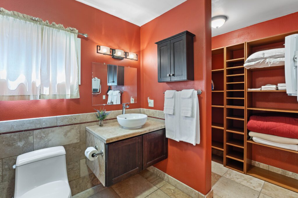 A bathroom with red walls and white fixtures.