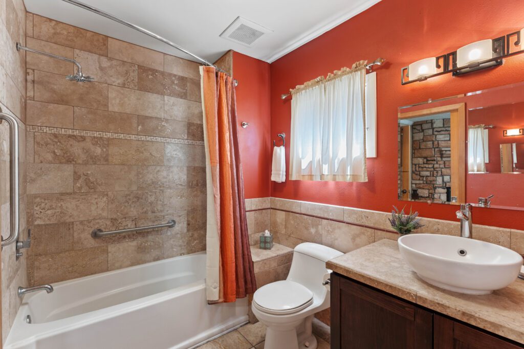 A bathroom with red walls and white fixtures.