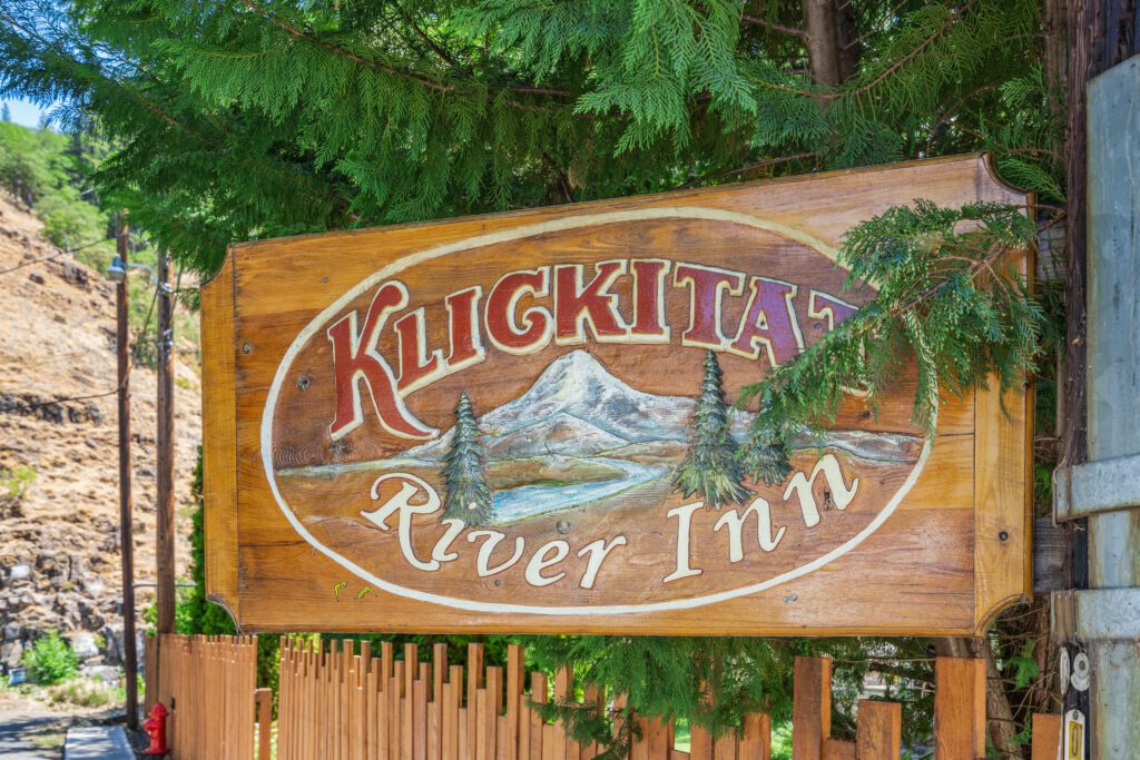Klickitat River Inn wooden sign with trees.