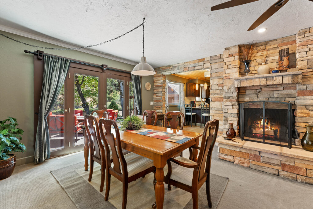 A dining room table with chairs and fireplace in the background.