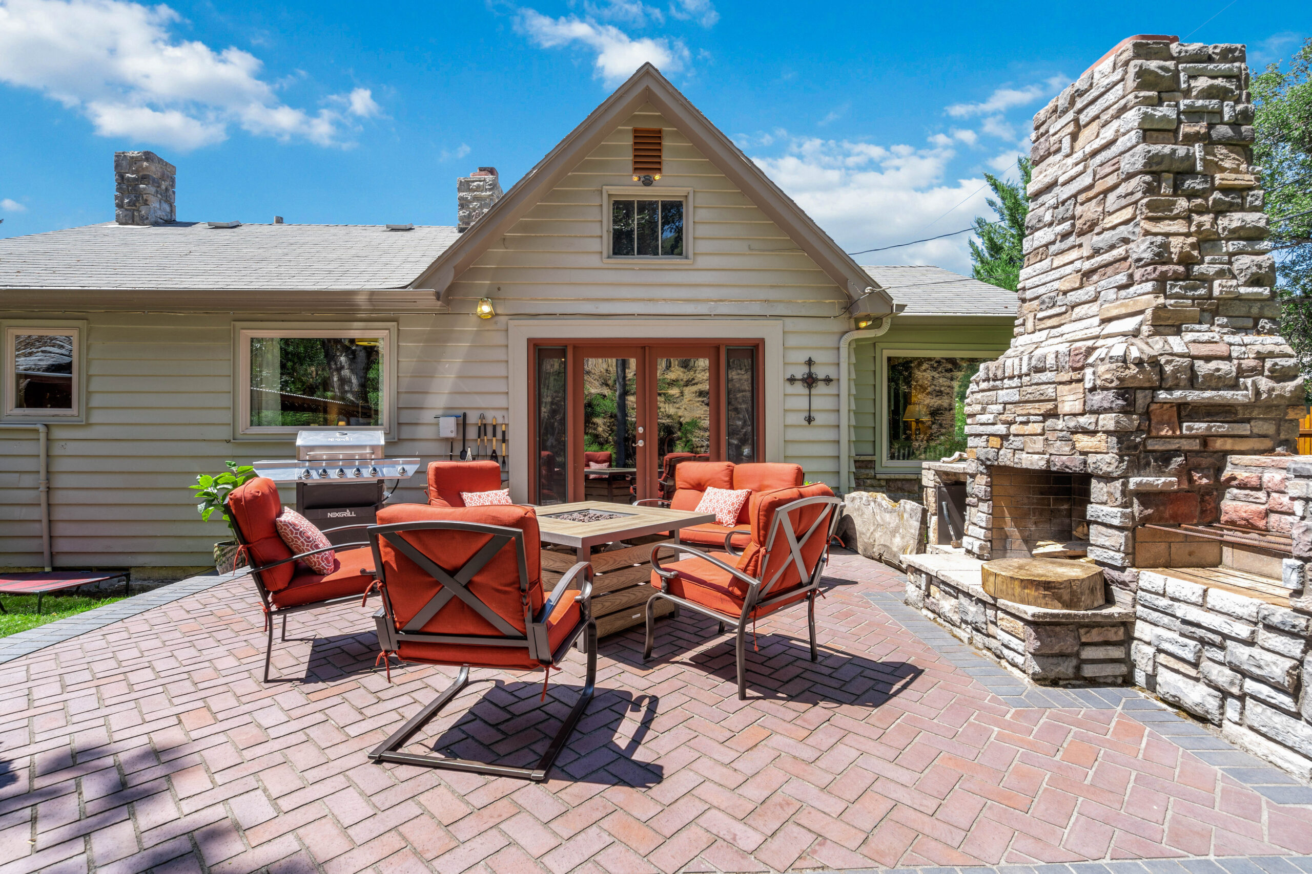 A patio with chairs and fire place in the middle of it.