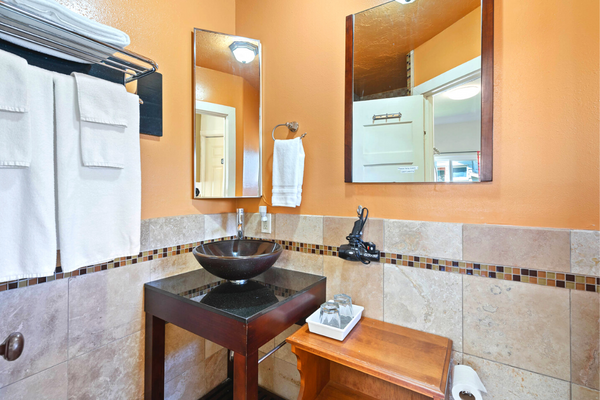 A bathroom with a sink, mirror and towel rack.