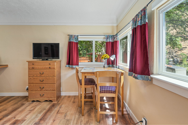 A room with a table and chairs, tv on the wall.