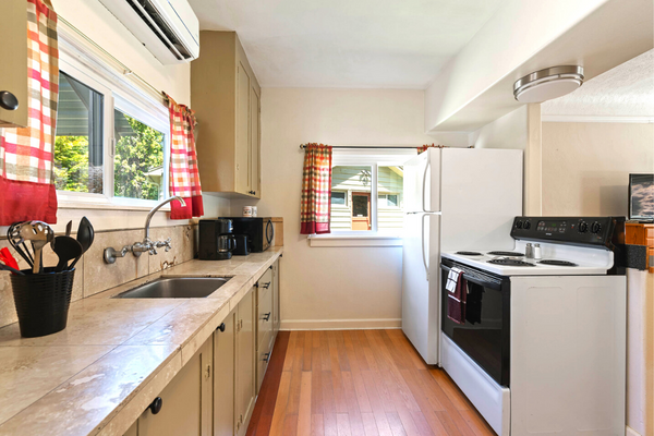 A kitchen with white appliances and wooden floors.