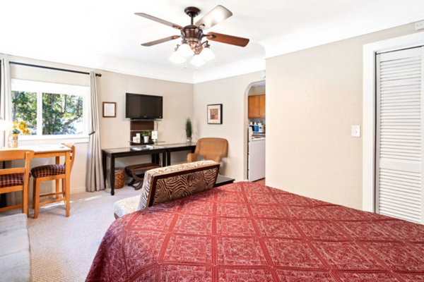 A bedroom with a bed, desk and television.