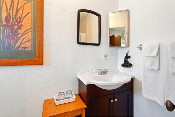 A bathroom with a sink, mirror and wooden cabinet.