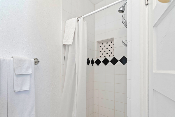 A white shower with black and white tile.