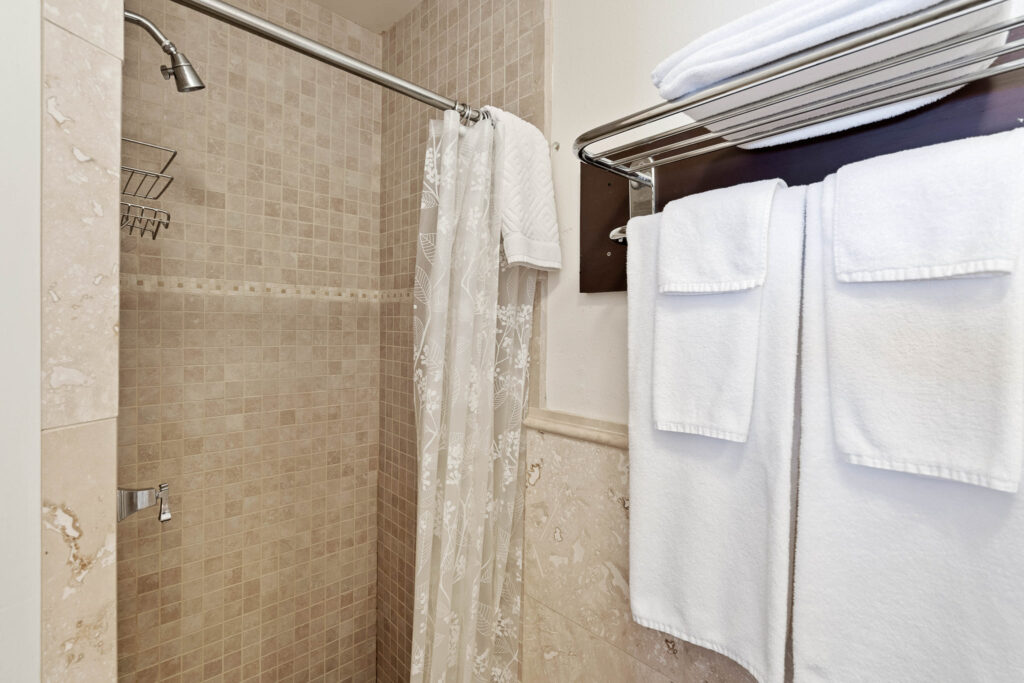 A bathroom with a shower and towels hanging on the rack.