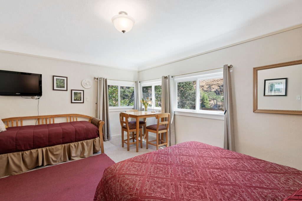 A bedroom with two beds and a dining table.